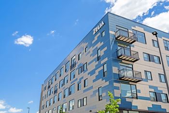 A modern building with a blue and beige facade and balconies on the upper floors.